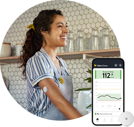 Smiling woman working in a coffee shop wearing a FreeStyle Libre 2 sensor