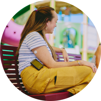 Woman sitting on a bench wearing a FreeStyle Libre 3 sensor and BetaBionics insulin pump