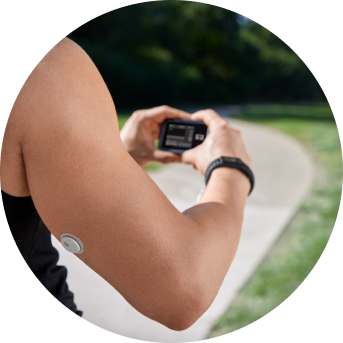 Woman looking at a t:slim X2™ insulin pump while wearing a FreeStyle Libre 3 Plus sensor