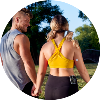 Man and woman walking in a park wearing a FreeStyle Libre 3 Plus sensor