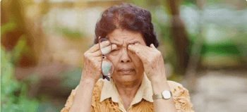 Người phụ nữ trung niên đang tháo kính và xoa mắt