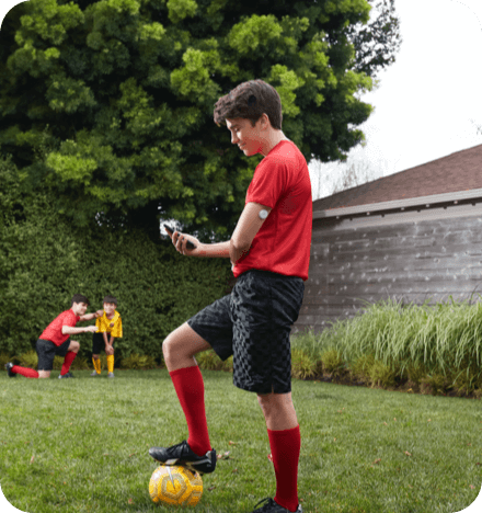 A boy in soccer kit checking his glucose readings on smartphone with FreeStyle Libre sensor visible on the back of his upper arm 