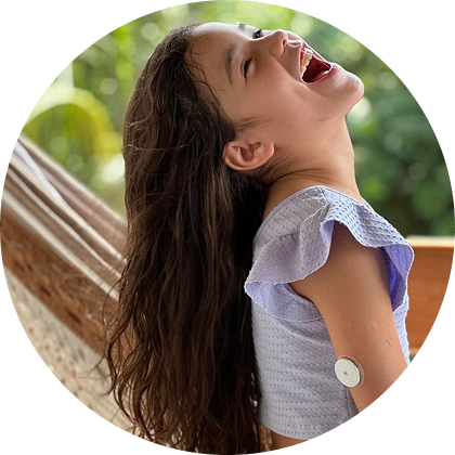 A little girl wearing a sensor and smiling