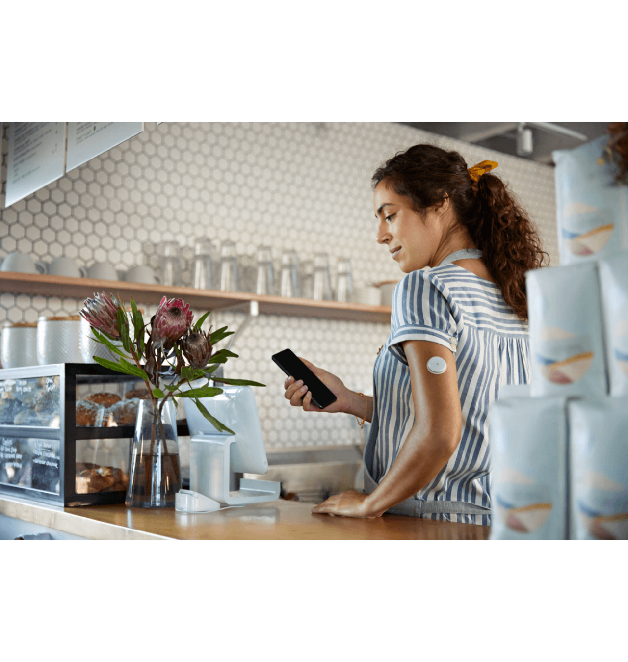 Κοπέλα με αισθητήρα, εργαζόμενη σε καφετέρια, που κοιτάζει το κινητό της