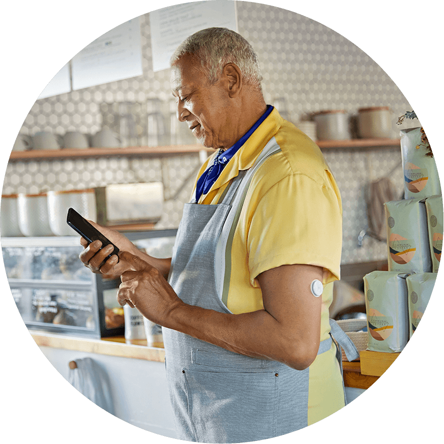 Man in an apron checking his phone and wearing FreeStyle Libre 2 Plus sensor