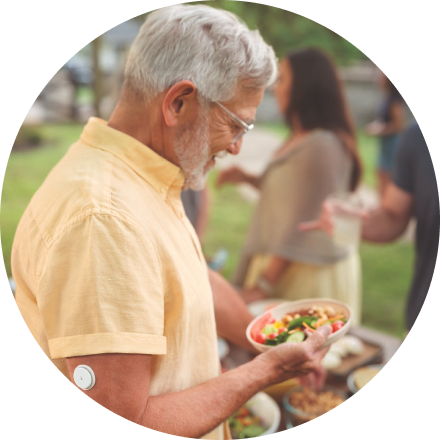 Man with sensor on upper arm holding a plate of food