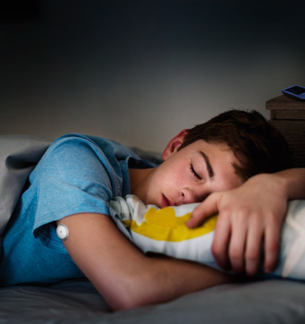 A child sleeping with FreeStyle Libre sensor visible on the back of his upper arm