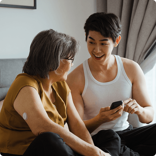 Un proche aidant et une personne portant un capteur FreeStyle Libre consultent les mesures sur un smartphone ou un lecteur