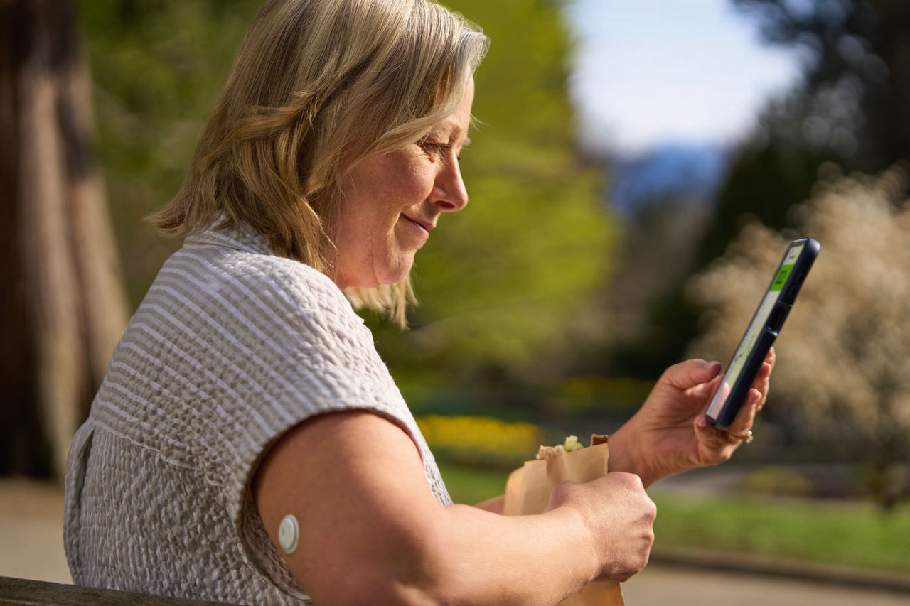 Woman with a FreeStyle Libre 3 sensor setting up th FreeStyle Libre 3 app on a smartphone