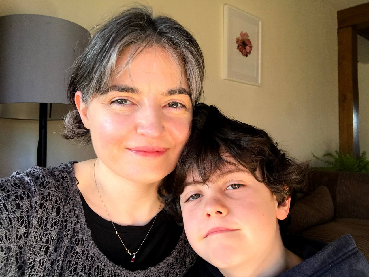 Mother & son side-hugging & smiling