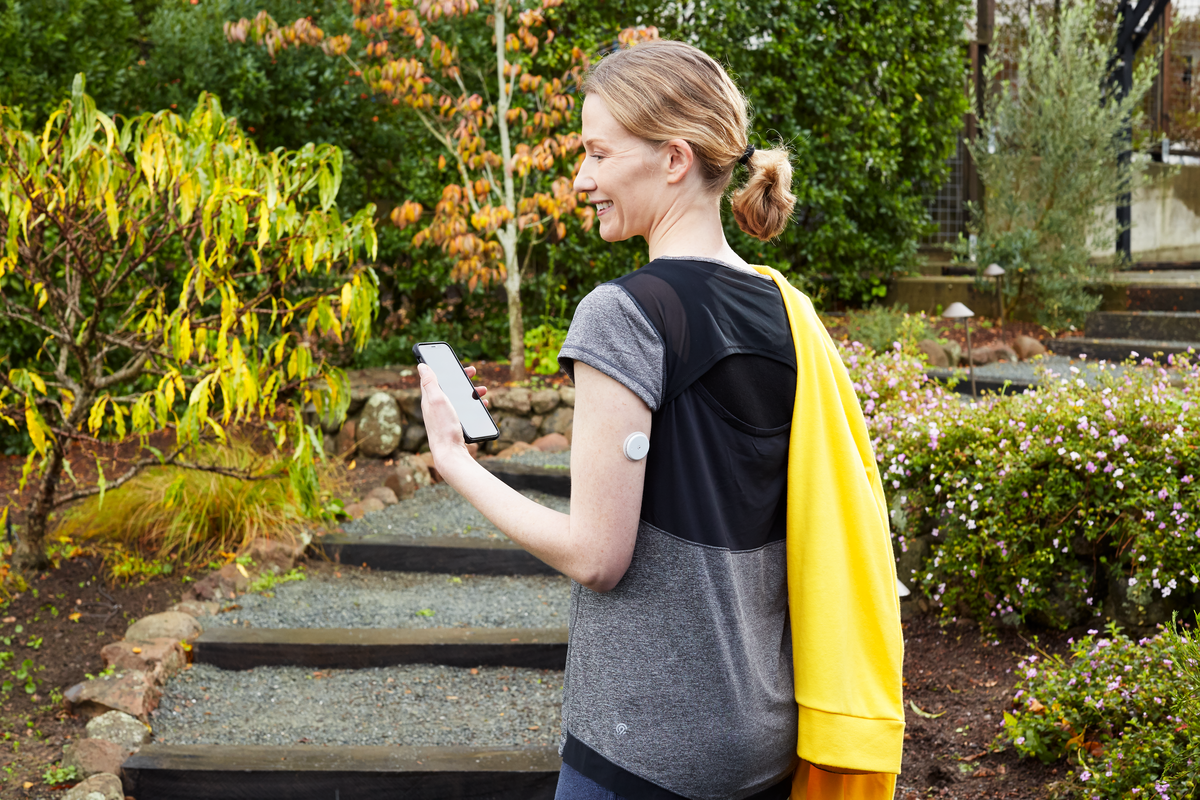 Woman with a FreeStyle Libre 2 sensor setting up th FreeStyle LibreLink app on a smartphone