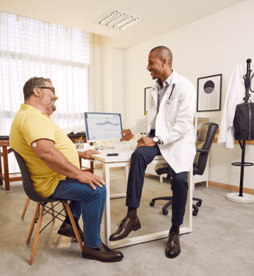  En vårdarbetare pratar med en man och ler.