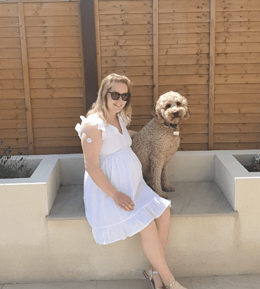 A woman sat in her garden with her dog. Her FreeStyle Libre sensor is visible on her arm.