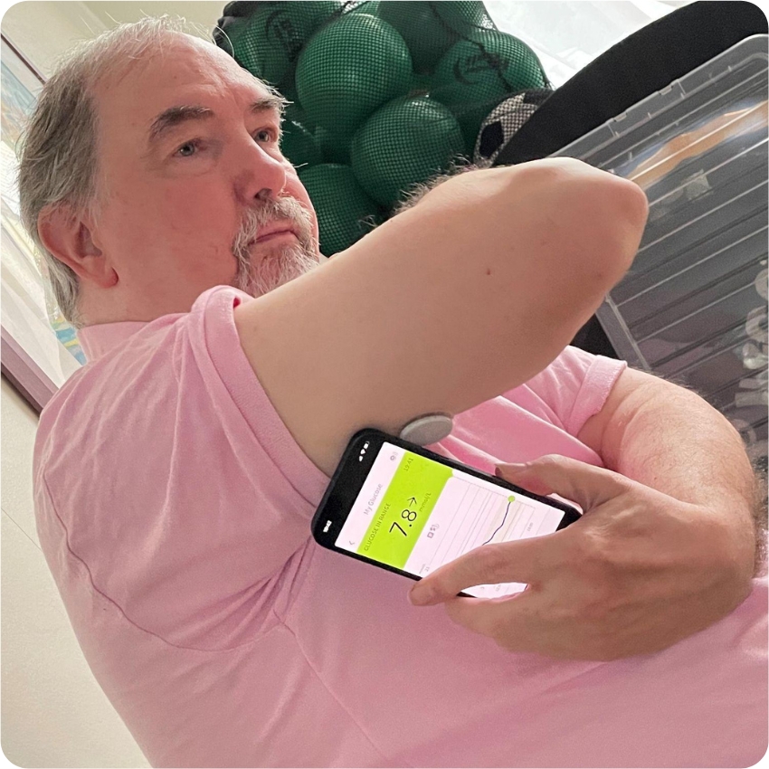 Ken Tait scanning FreeStyle Libre 2 sensor on the back of his upper arm with the FreeStyle LibreLink app on his smartphone