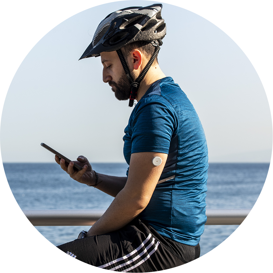 Man with sensor on his upper arm, sitting on his bike and checking his phone
