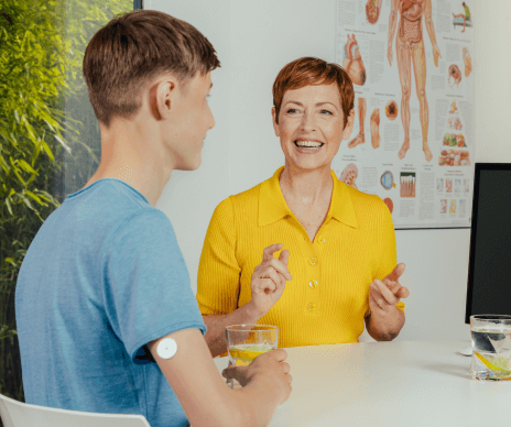 An HCP smiling and talking to a man with his sensor visible on the back of his upper his arm