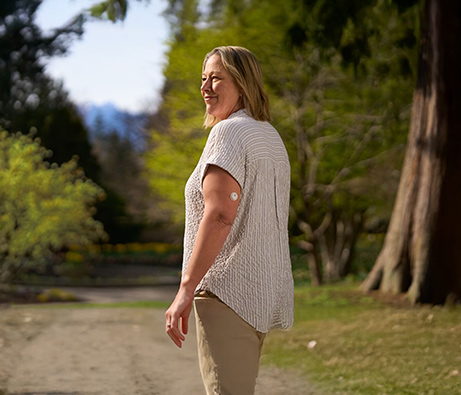 Lady with sensor on her upper arm walking in the woods