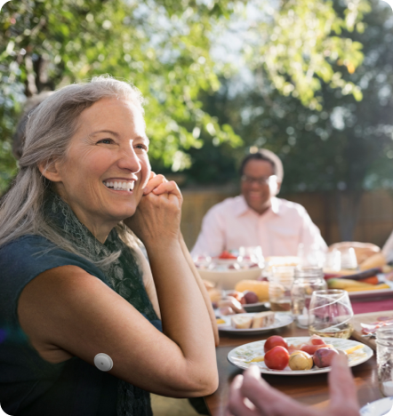 A woman eating outside and smiling.