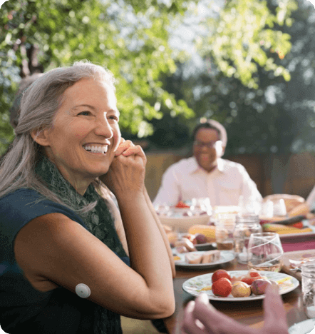 A woman eating outside and smiling.