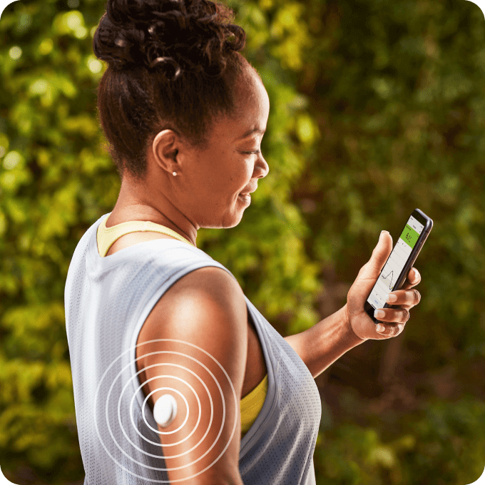 Woman with a FreeStyle Libre 2 sensor setting up th FreeStyle LibreLink app on a smartphone