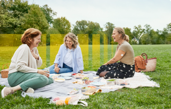 A group of women eating a picnic in a field. One of the women is wearing a FreeStyle Libre sensor