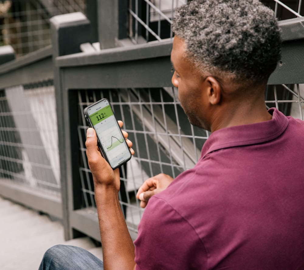 Man holding phone with FreeStyle LibreLink app