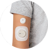 Comparison of the size of the smaller FreeStyle Libre 3 Plus sensor vs. the larger Dexcom G7 sensor on a person's arm