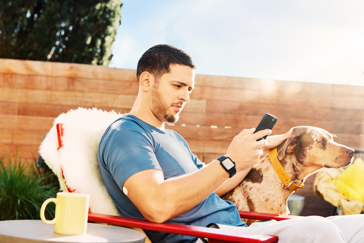 Man wearing a FreeStyle Libre sensor, having a coffee outside with his dog